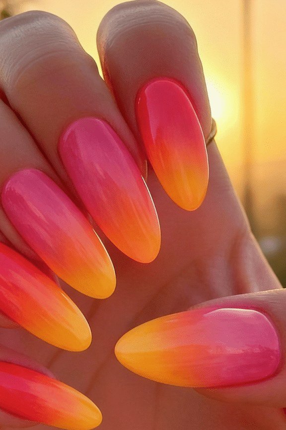 Neon Sunset Almond Ombre - Electric pink fades into tangerine on these medium almond nails, glowing against a beach backdrop.