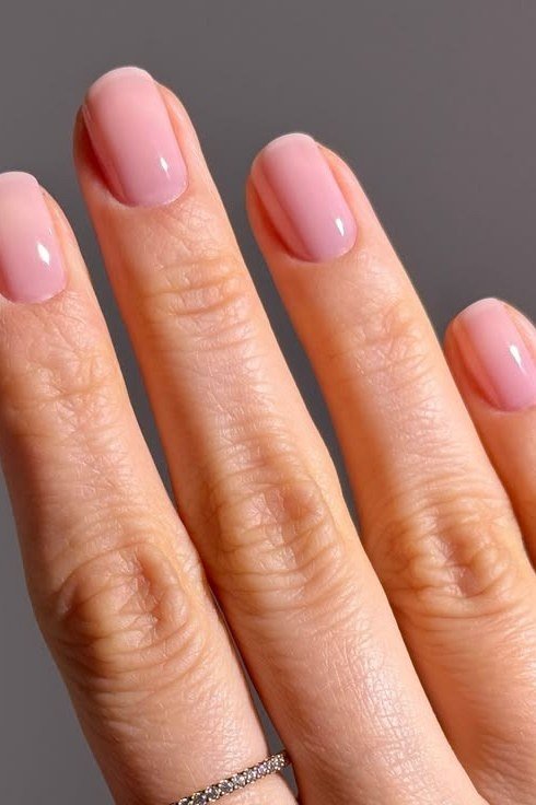short oval, glossy baby pink, single hand on gray background , for women over 60