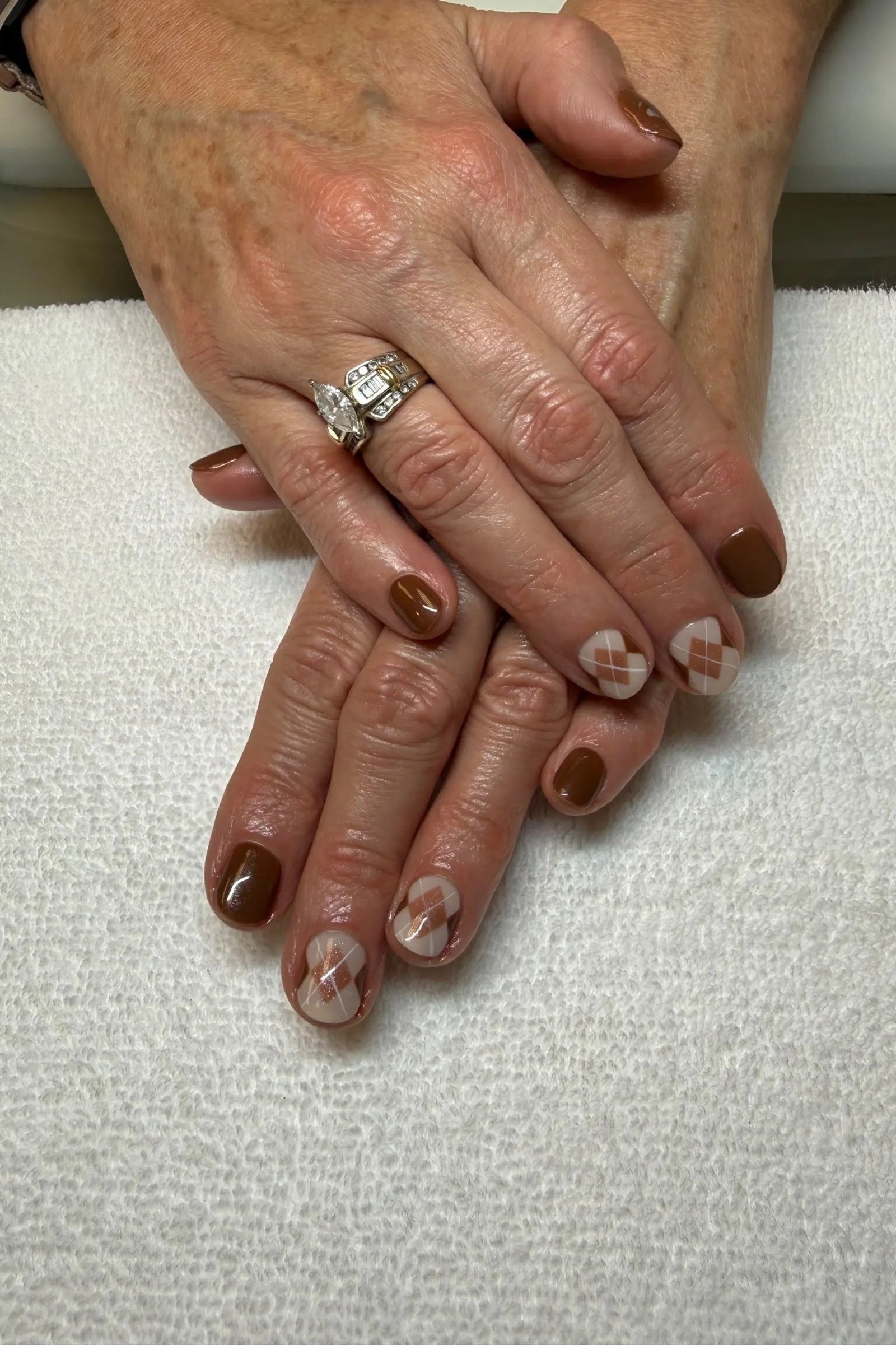 Taupe and brown mixed short gel nails with plaid art on older hands, cozy fall manicure