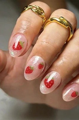 Sheer nude oval nails with strawberry accent and gold rings