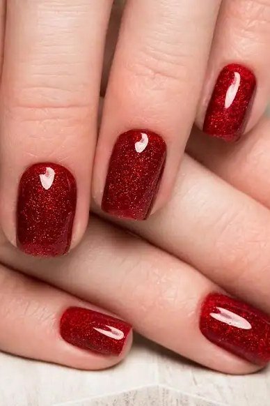 Glittering ruby red nail polish closeup