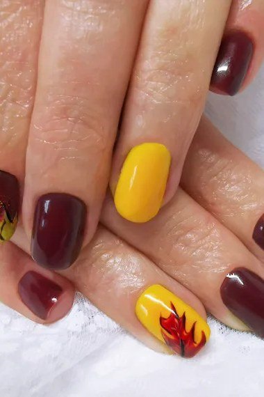 Burgundy and mustard yellow short nails with sunflower nail art, glossy fall contrast.