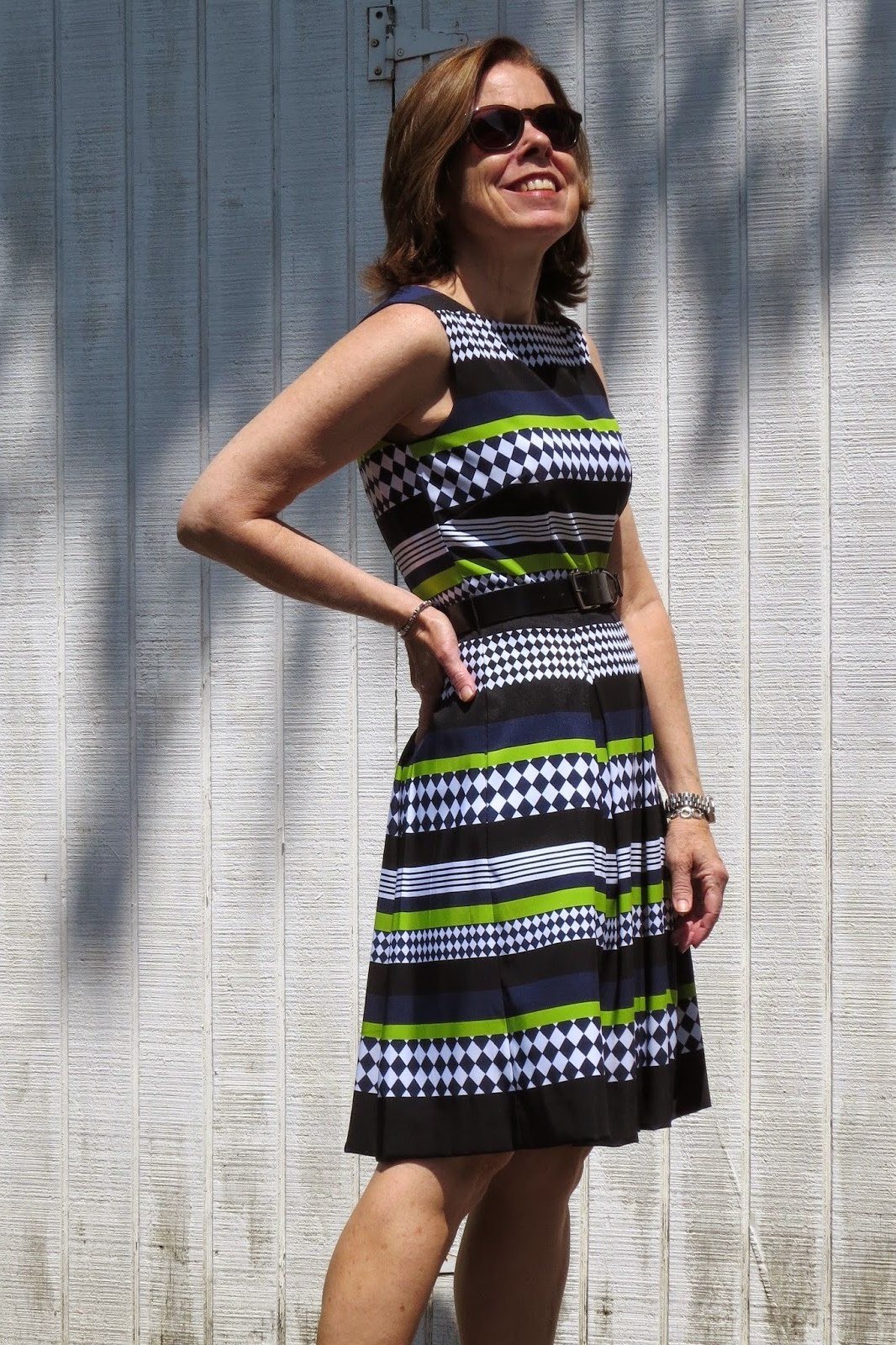 Woman in a black-white-and-green striped sleeveless midi dress, industrial wall - summer dress for women over 50