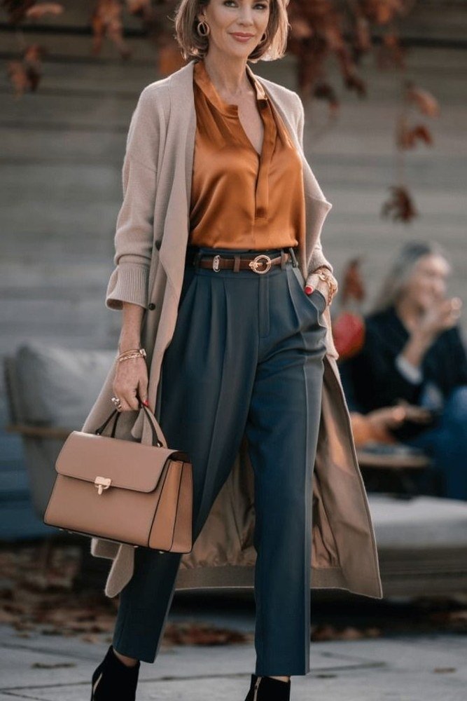Rust blouse with teal trousers and camel coat for women over 50, fall date night outfit