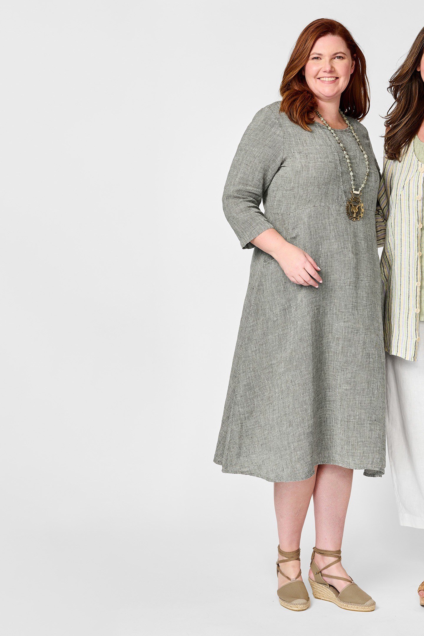 Two older women in sage linen tunics and white pants