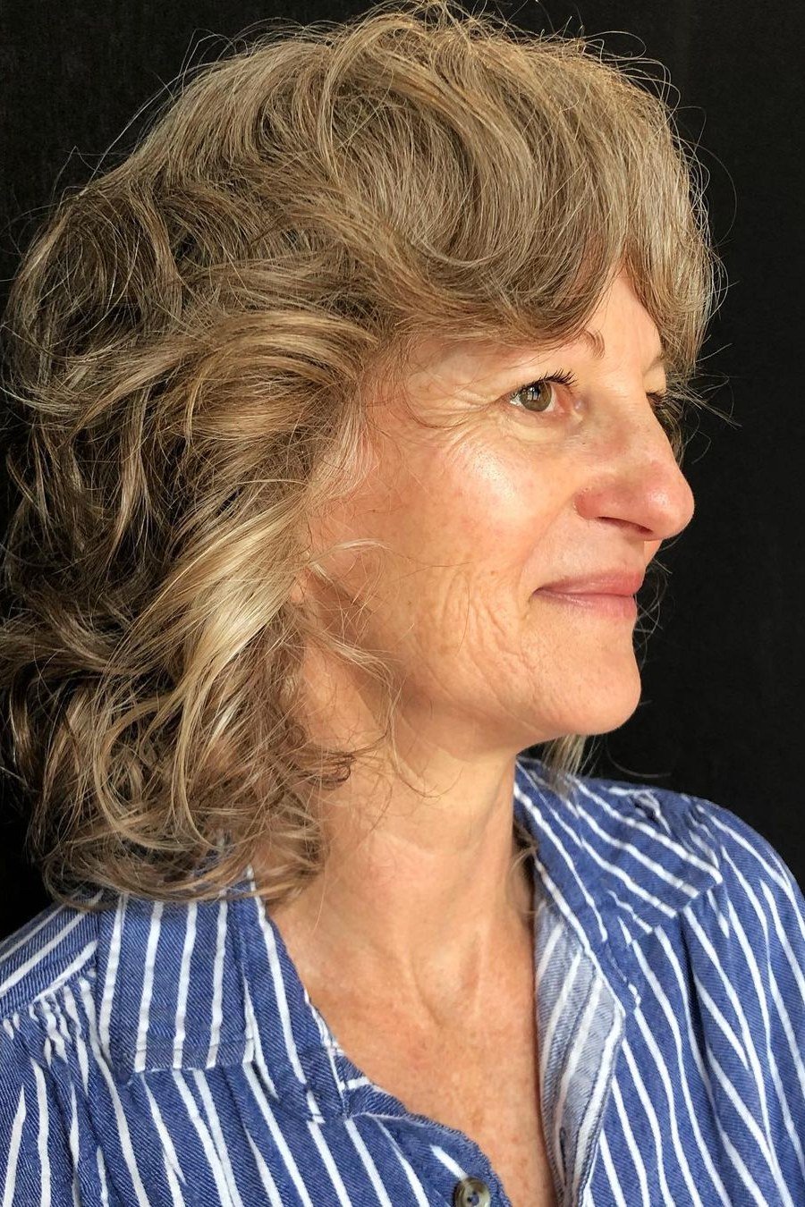Curly blonde hair on an older woman in side profile, medium hairstyle for women over 60