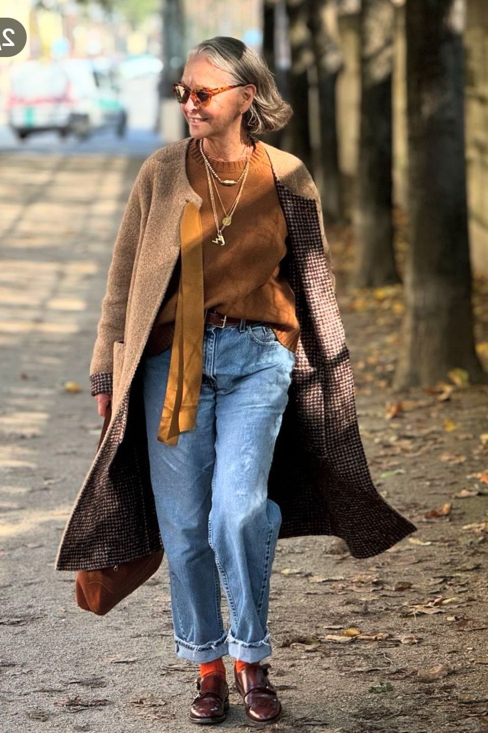 Brown plaid oversized coat over rust sweater with blue jeans and red boots