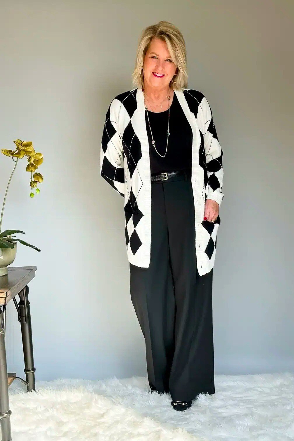 Black white argyle cardigan black wide pants, blonde woman indoor - business casual work outfit for women over 50