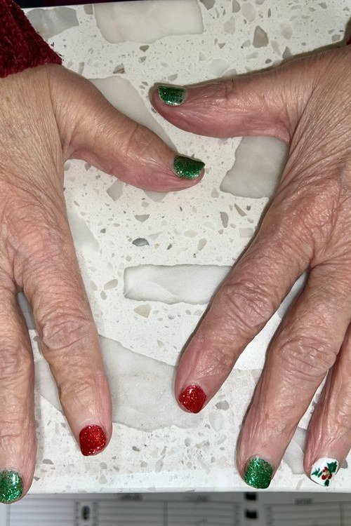 Mature hands with red and green tipped nails - Christmas nail design for older women