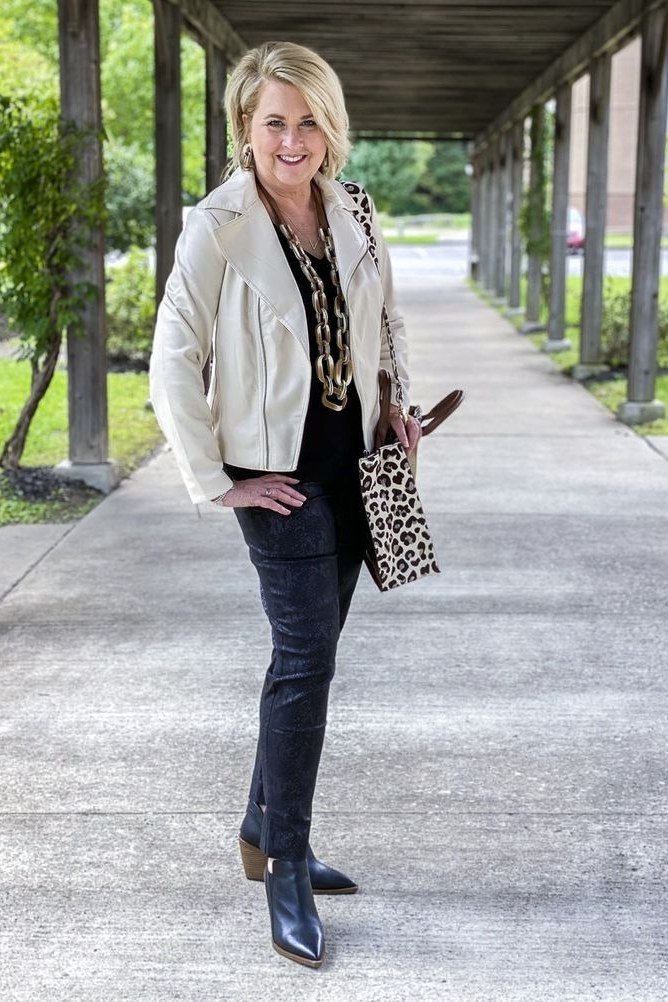 Fall city outfit for women over 50: white moto jacket leopard scarf dark jeans
