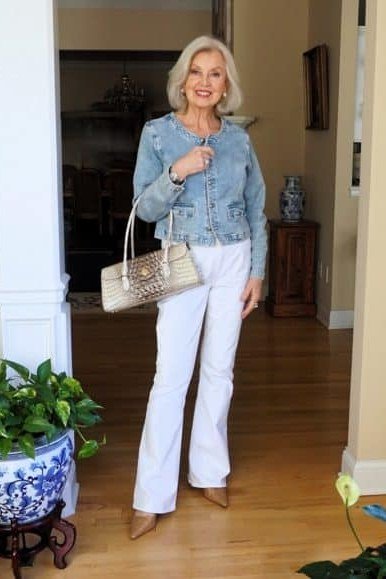 Woman over 50 wearing light denim jacket with white jeans and cream bag, everyday casual outfit idea