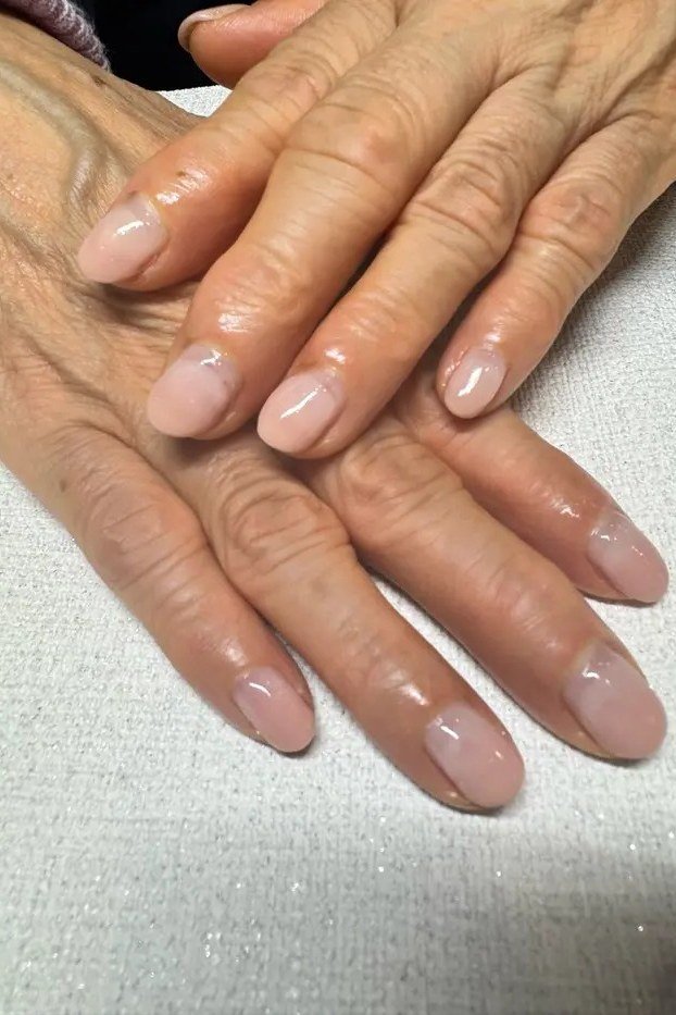 Glossy nude pink nails on mature hands for women over 50