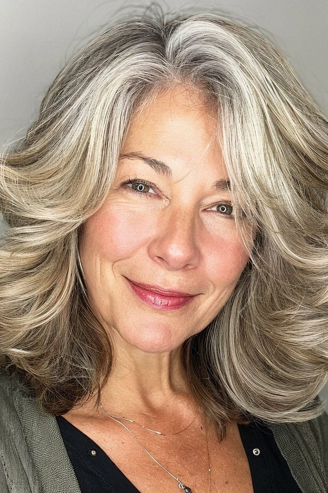 Bouncy blonde blowout wavy layered medium-length hairstyle, front view, for women over 50