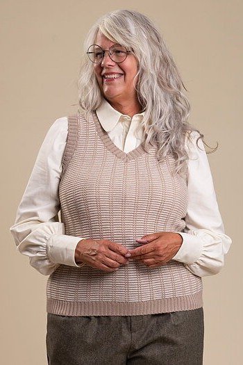 Taupe ribbed knit vest over white shirt on beige backdrop, cozy sweater outfit idea for women over 70