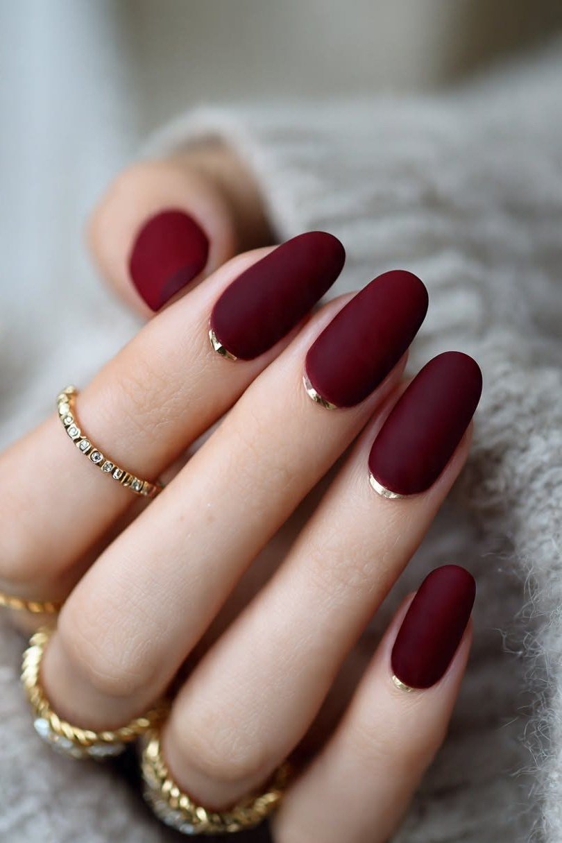 Glossy burgundy short nails with gold rings for women over 50