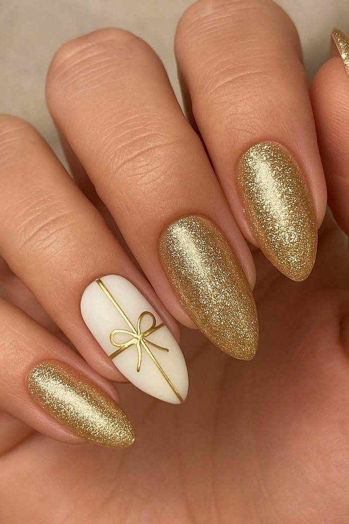 gold glitter nails with white bow accent nail