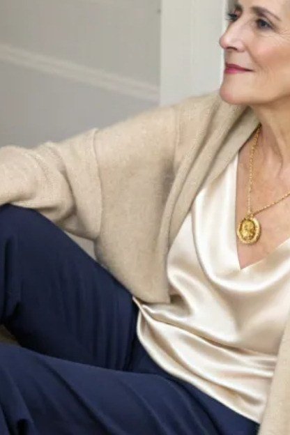 Older woman in cream knit cardigan over navy top