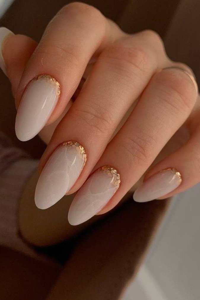 Milky white nails with gold glitter along the cuticle