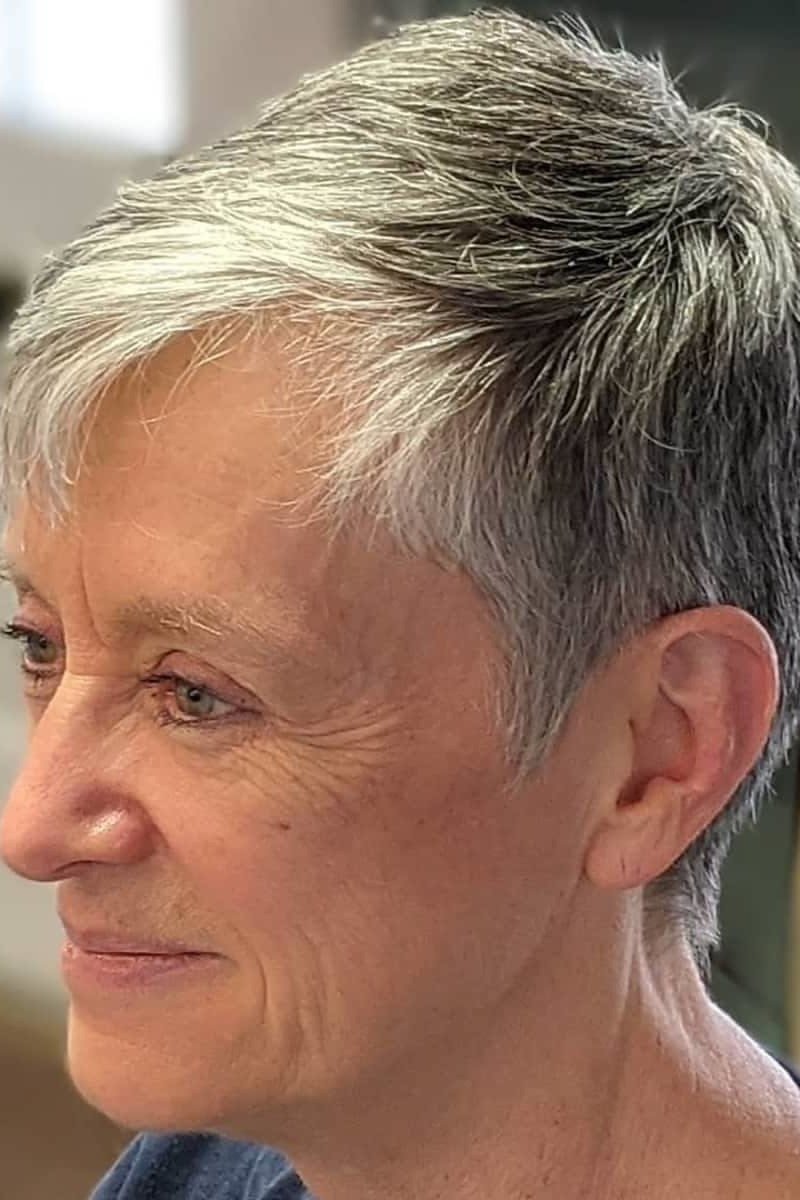 Salt and pepper wispy pixie with soft layers and gentle smile