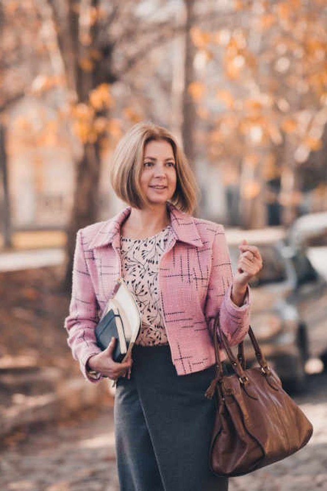 Pink floral blazer with dark trousers and brown handbag on a fall street