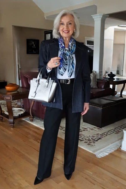 Woman over 50 in a navy blazer with a patterned scarf and a silver tote