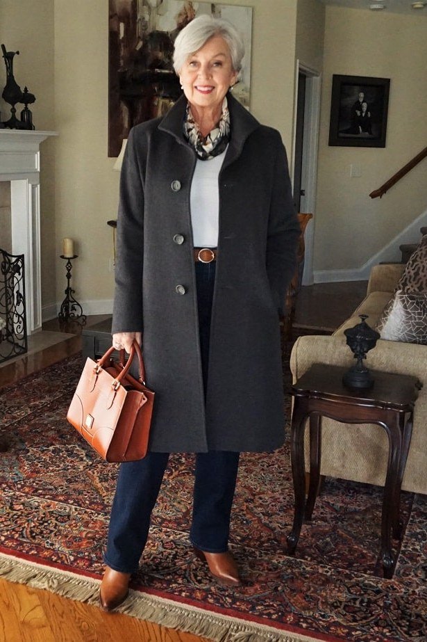 Black knee-length coat with white top and dark jeans for women over 50