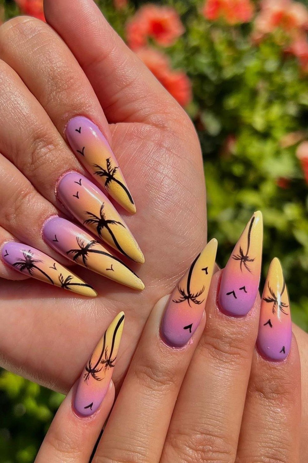 Sunset Palm Silhouette Stiletto Nails - Purple and golden yellow fade across these long stiletto nails, with delicate black palm trees and tiny birds silhouetted on top. The glossy finish gives the tiny scene real depth.
