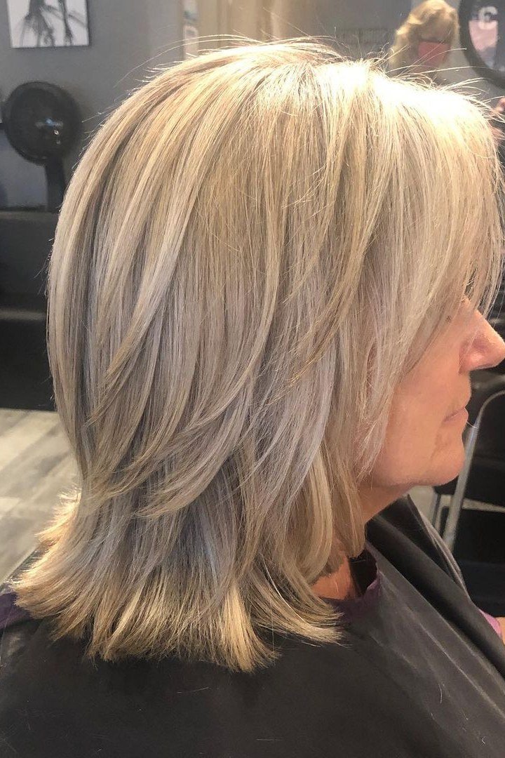 Layered blonde salon haircut on an older woman, side view, medium hairstyle for women over 60