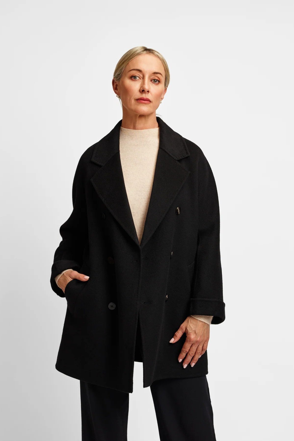 Black oversized coat over a beige top for women over 50 at work