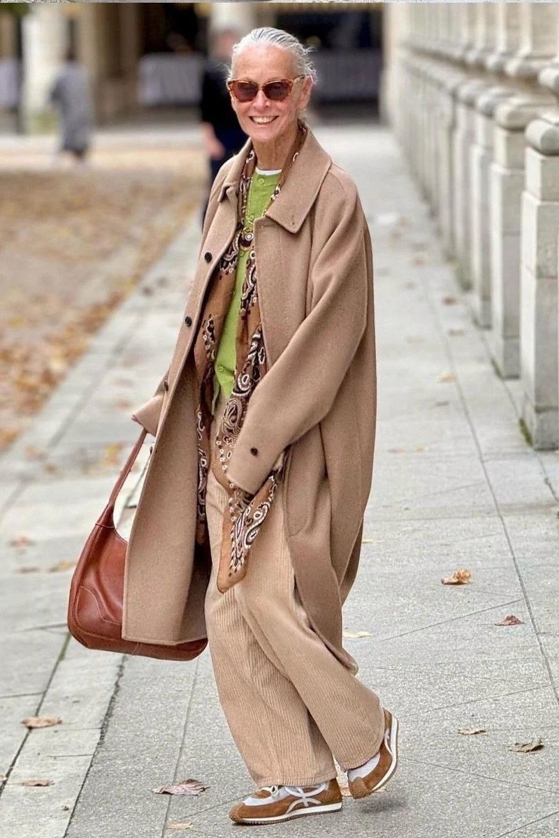 Casual fall outfit for women over 60: cream puffer vest, burgundy sweater, dark jeans