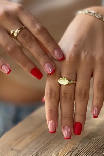 Red and nude french tip combo on hands with gold rings for women over 70