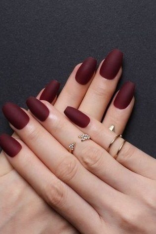 Matte burgundy nails with delicate gold rings for women over 50