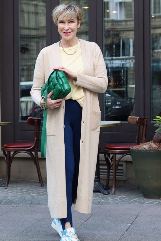 Woman over 50 wearing cream cardigan with yellow top and navy pants, everyday casual outfit idea