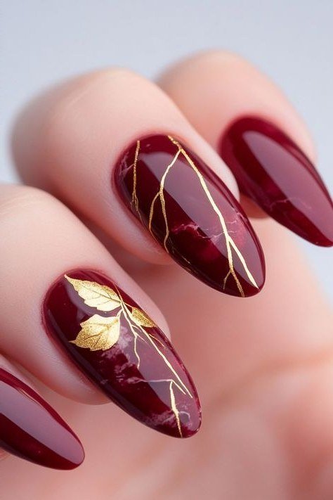 Gold line art on burgundy almond, burgundy fall nail idea for women over 60