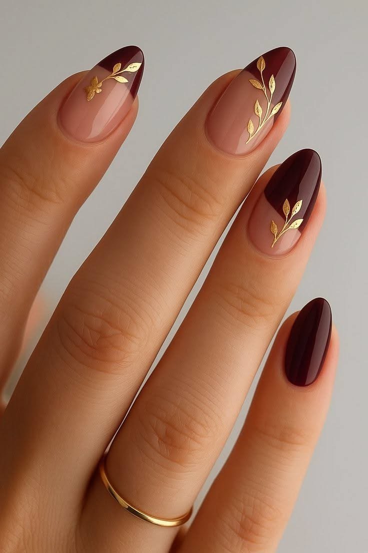 Burgundy french tips with gold leaf art on nude base, almond shape, medium length, glossy, fall nail color for women over 40