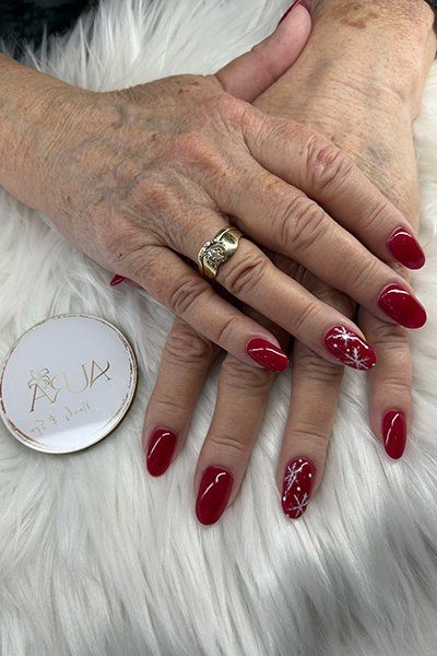 Red with white snowflake accents, mature hands - Christmas nail design for older women