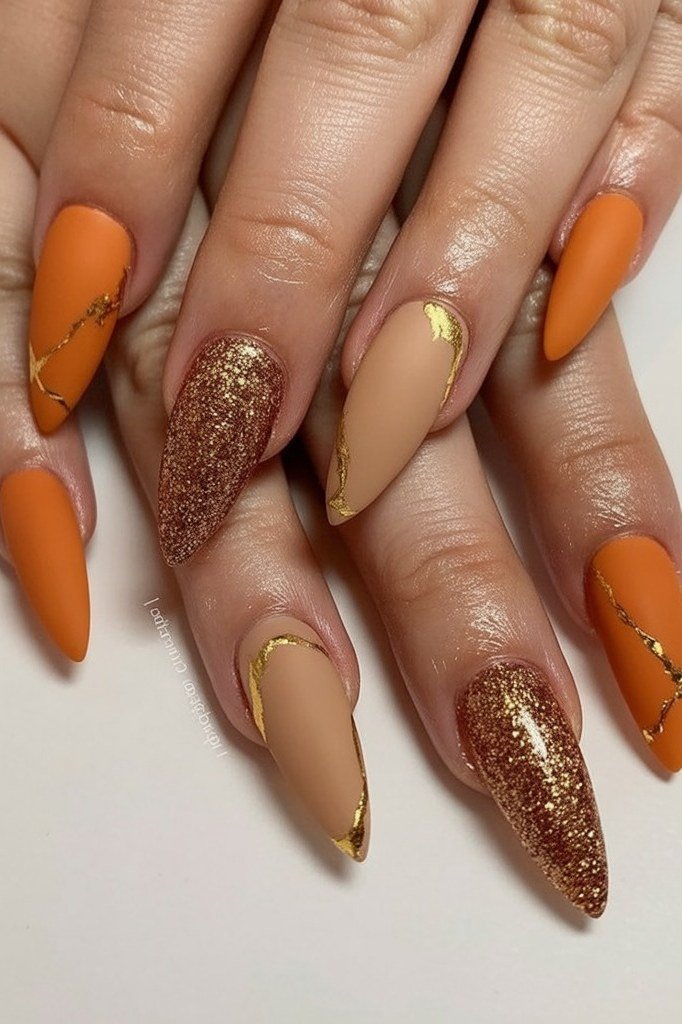 Burnt orange gel nails with copper glitter and gold accents, sparkly fall manicure