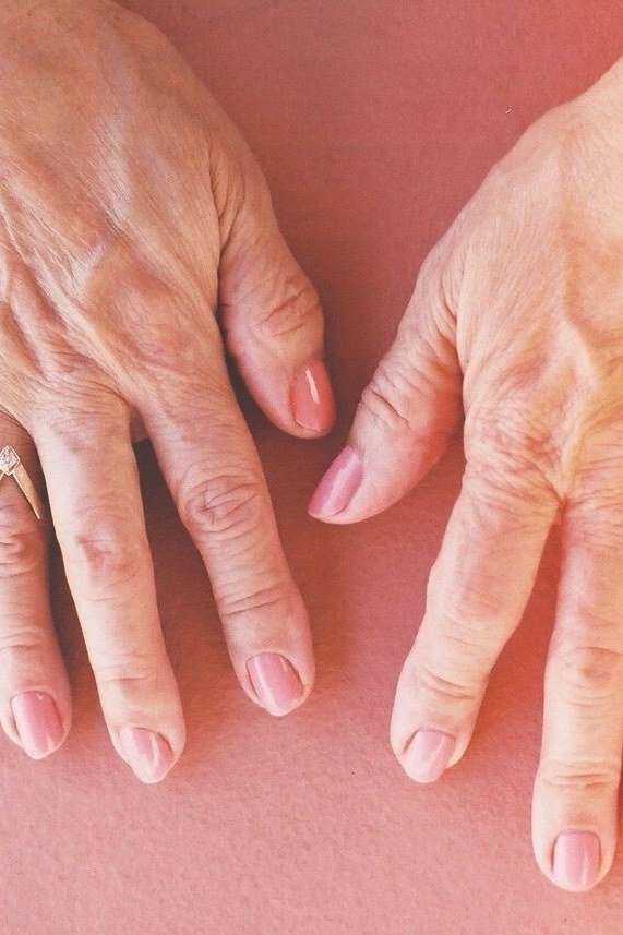 sheer pink nails on a pink backdrop for older women