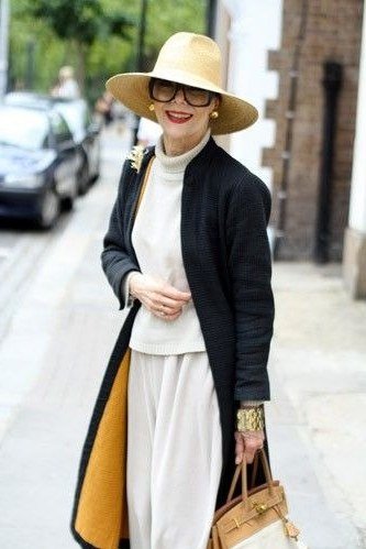 Casual fall outfit for women over 60: tan trench coat, striped sweater, indigo jeans