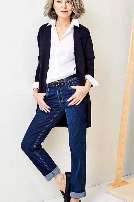 Woman over 60 wearing white shirt, navy cardigan, medium jeans, black loafers