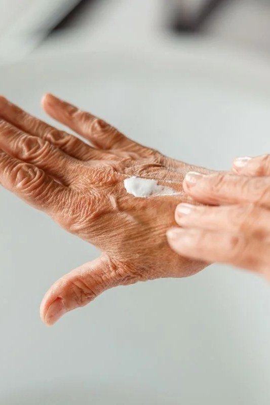 Applying night hand cream to mature hands