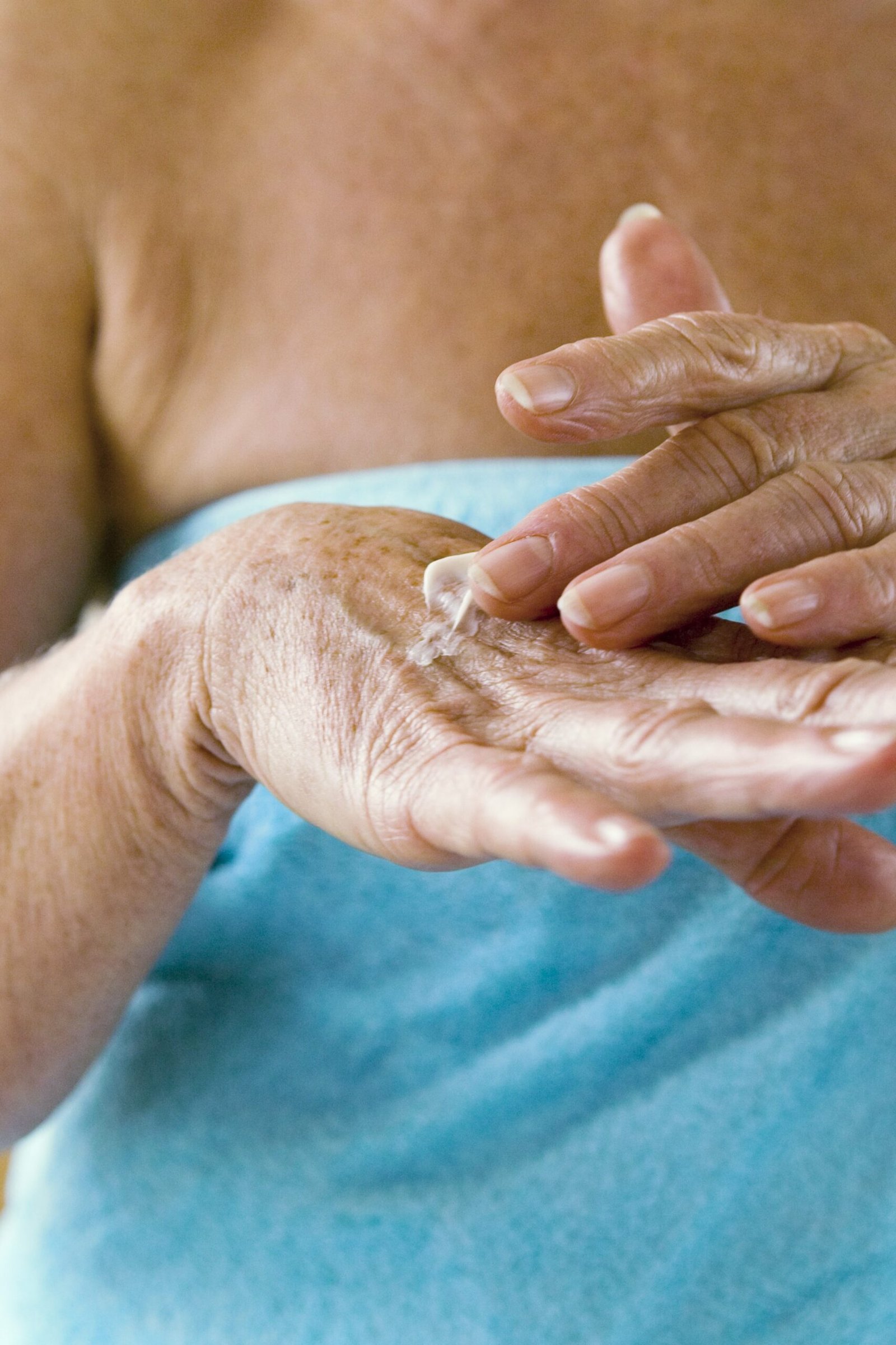 Applying hand cream after washing mature hands