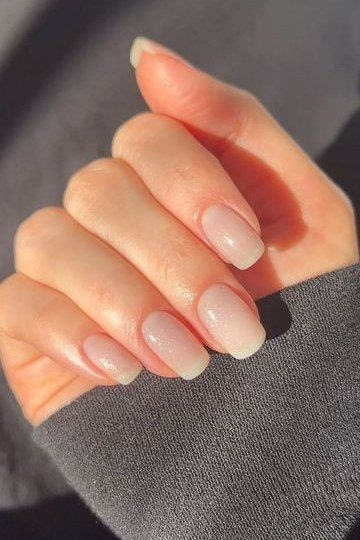 Warm milky nude polish on short nails in sunlight