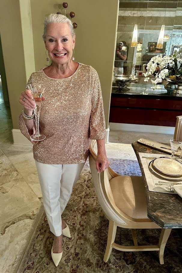 holiday evening outfit for women over 60: gold sequin top with white trousers