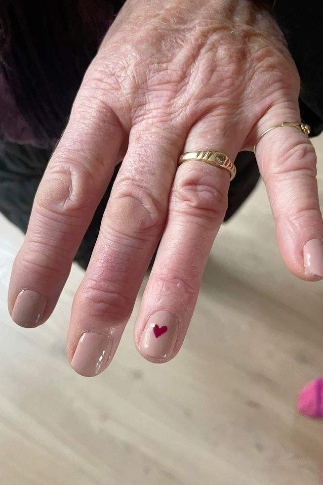 Nude nails with tiny red heart art for older women