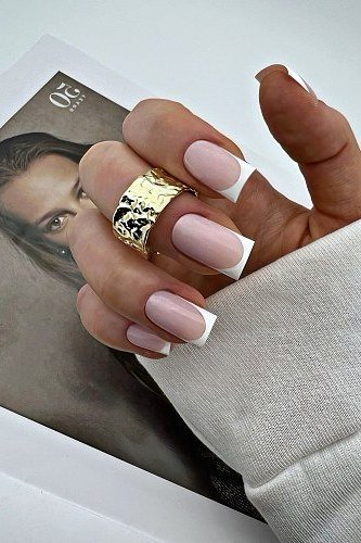 French manicure with a gold ring styled with a magazine