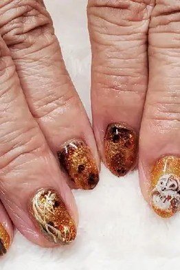 Tortoiseshell and gold leaf nail art on elderly hands, fall nail design for older women