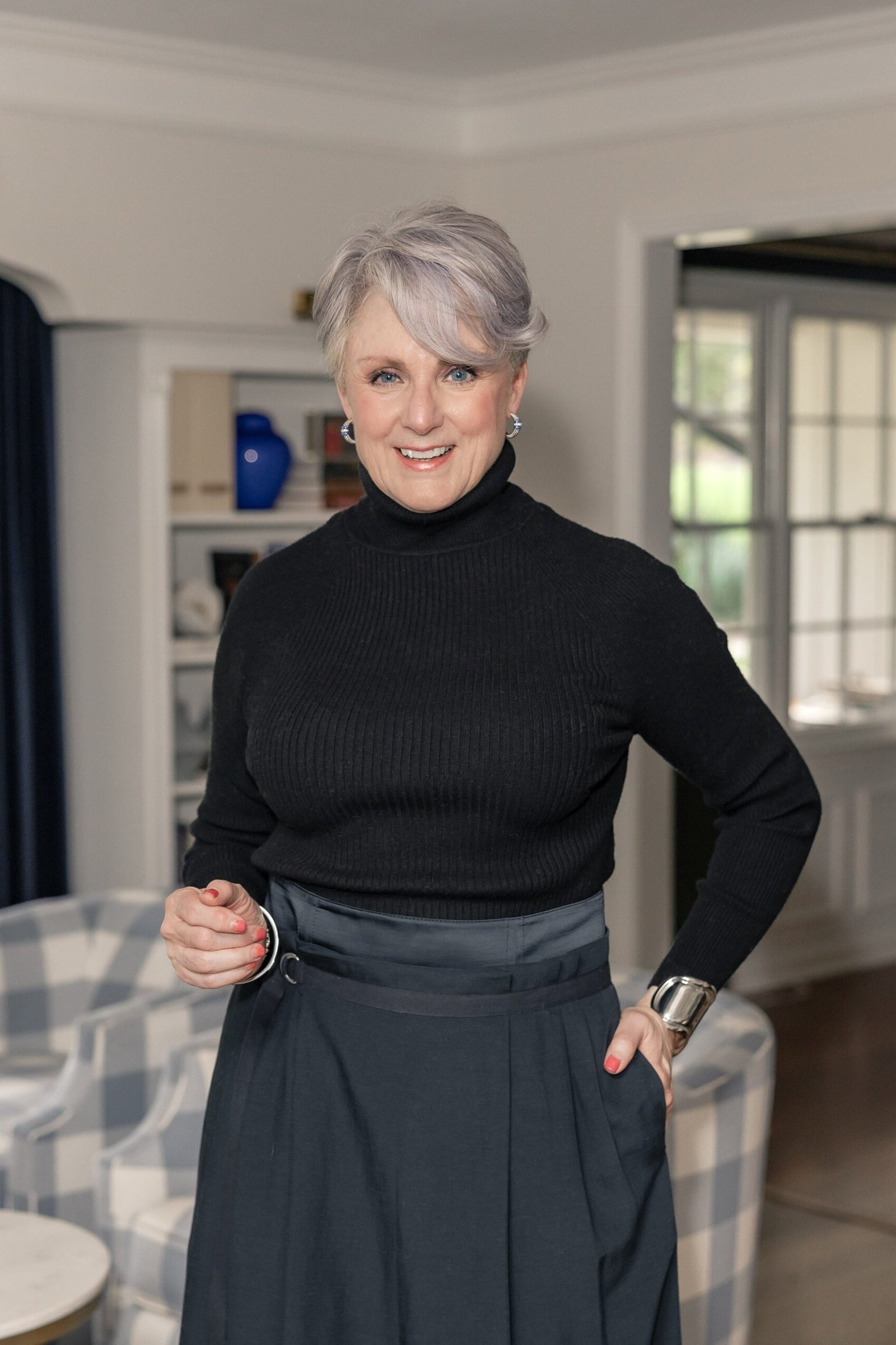 Black turtleneck with dark midi skirt in an interior