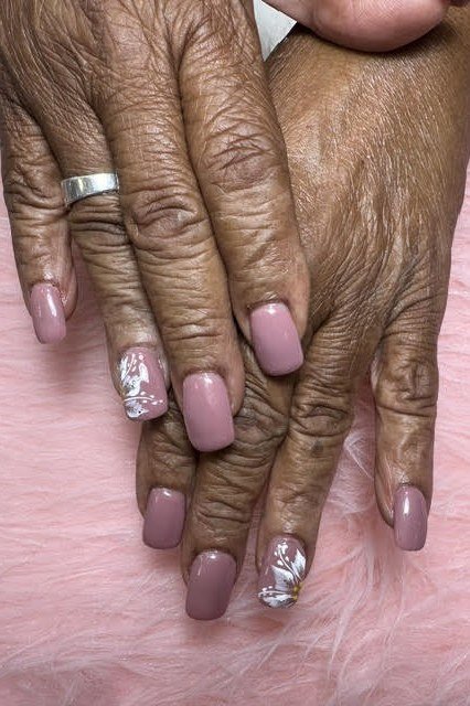 Mauve nails with silver foil accents on elderly hands