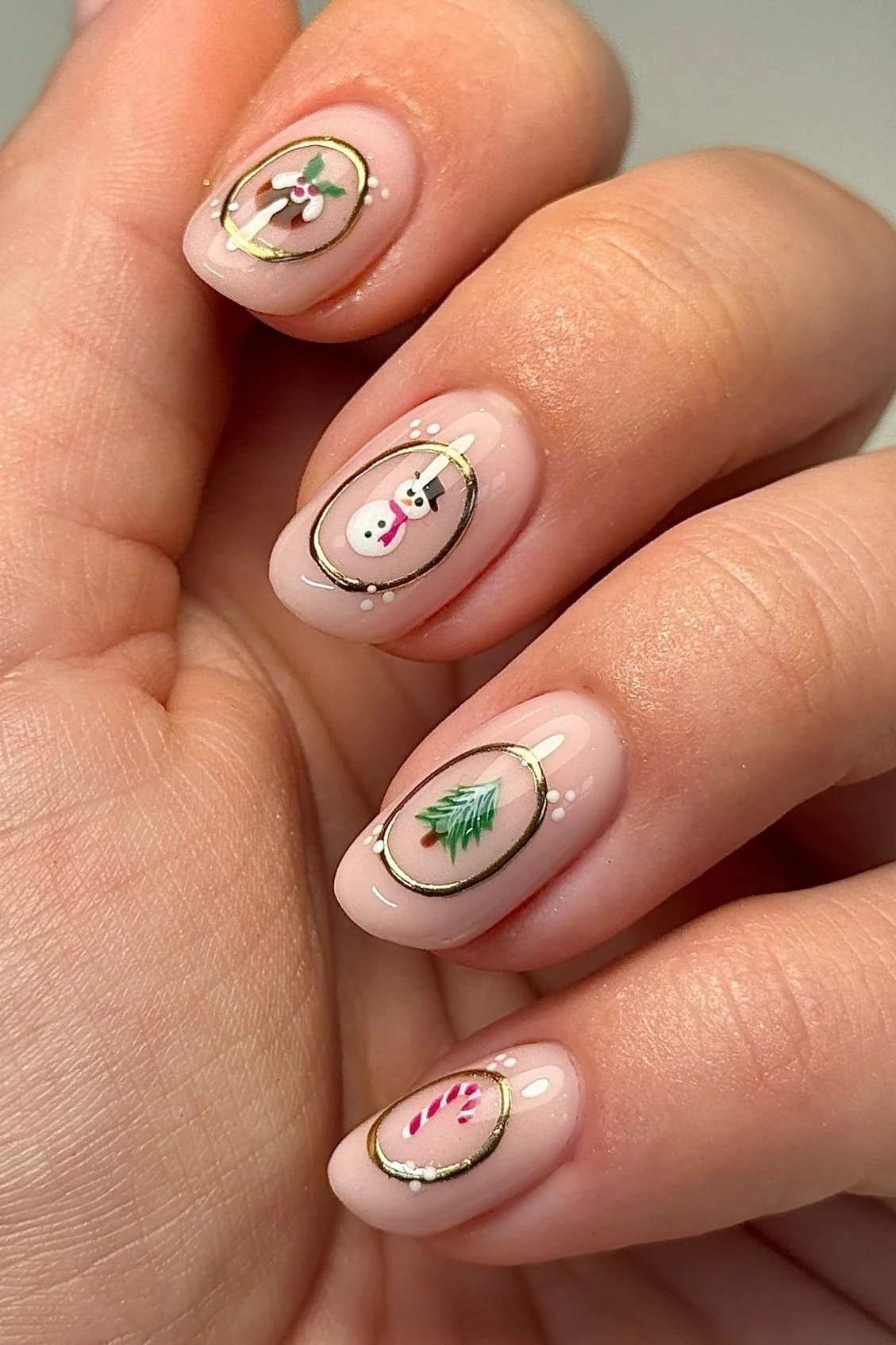 Nude nails with gold-trimmed Christmas tree and floral art - classy Christmas nail idea for women over 70